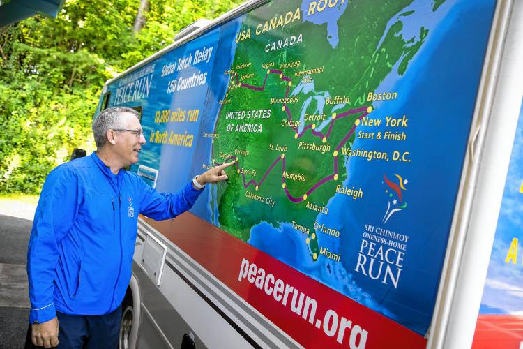 Shalil Wilson points to all the places the Peace Run group has traveled in the United States on the side of their RV on Monday.