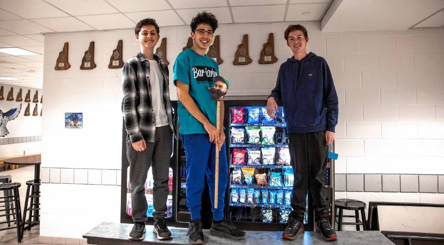 Bow players Carter Monroe, left,  Mathias Hanson, and Matthew Kropp had to get up on a table to see their award in the hallway of Bow High School library on Wednesday.