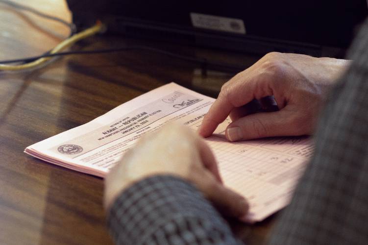 A NH Secretary of State official Dan Cloutier checks ballots matching them with the electronic tallies in the Executive Council Chambers at the State House on Jan. 24.