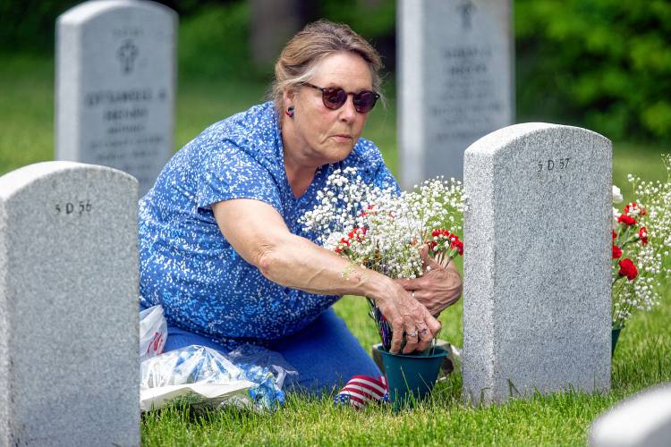 Patricia Skidmore puts flowers on her husband, Thomas Skidmore’s marker at the New Hampshire Veterans Cemetery on Thursday, May 23, 2024. Skidmore served in the Vietnam War.