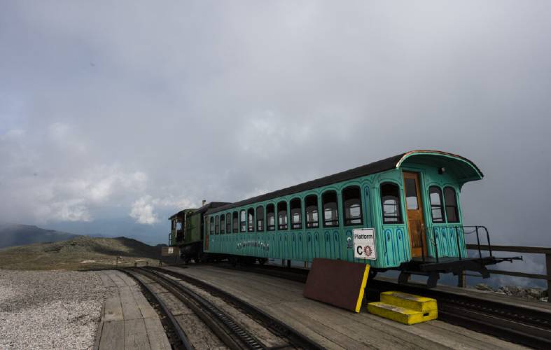 A Cog Railway train car sits at the summit of Mount Washington, waiting to bring passengers back down the mountain.