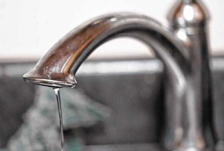 A trickle of water comes out of a faucet. A trickle of water comes out of a faucet.