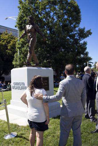 Christa McAuliffe’s children, Caroline and Scott, look up at their mother’s statue after the unveiling at the State House on Monday on what would have been her 76th birthday.