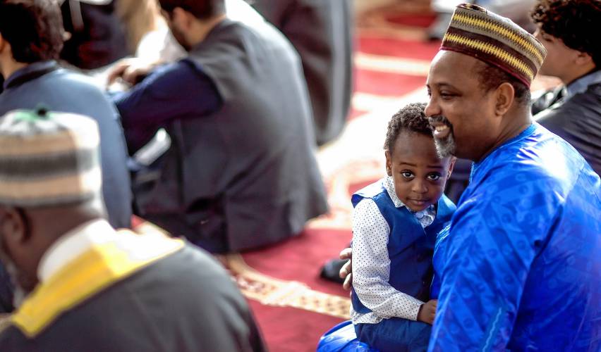 Abdul Rashid sits with his father, Hamidov Yaya during the Eid al-Fitr service at the IQRA Islamic Society of Greater Concord. Eid al Fitr is  one of the holidays celebrated by Muslims and commemorates the end of the holy month of Ramadan, in which Muslims fast daily from before dawn until sunset.