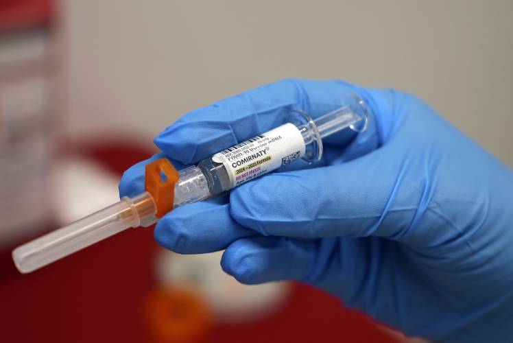 A pharmacist holds a COVID-19 vaccine at a pharmacy in New York, on Tuesday, Sept. 24, 2024.