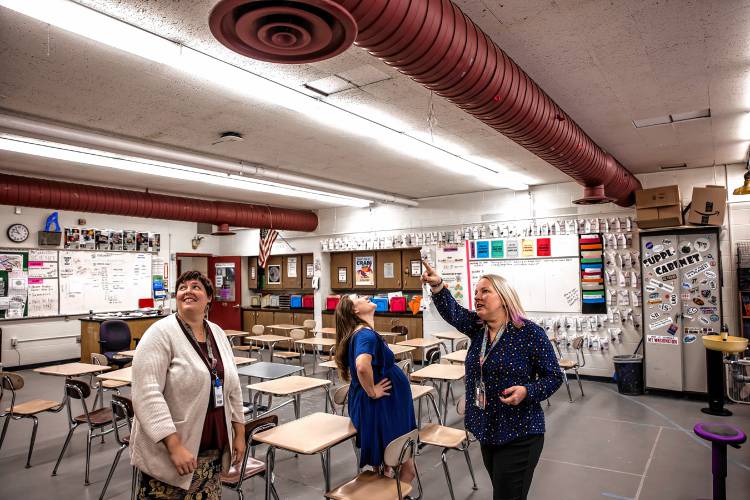 Rundlett science teachers Michelle Ruopp, left, and Sarah Grant, center, look up on Monday as fellow teacher Amy Schaeffner points to the area where water comes through and where a bird laid six eggs in her classroom.
