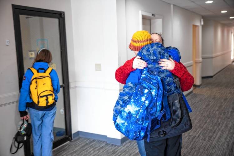 Amber MacQuarrie hugs her son, Ethan, as her daughter, Olive, waits for the KaiPod Learning Center in Manchester to open on Friday, Feb. 21.
