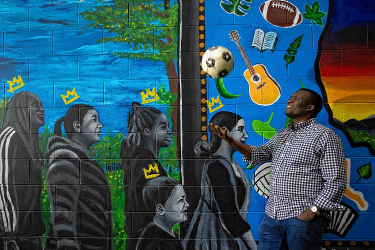 Jean Hakuzimana, founder and director of the organization NH Songa, throws up a soccer ball in front of the mural at Keach Park, the site of the Multicultural Festival on Sunday. Hakuzimana feels the park is the center for the New American culture in Concord and he is happy that the festival moved to the park from the State House.The organization's name means ‘to move’ in Swahili. Hakuzimana hopes NH Songa will foster more support for New Americans in the workforce through what he calls “Moving Together Conversations.” “I feel that two communities connected by immigration and hospitality would need to find a way to move together for a common destiny,” he said.