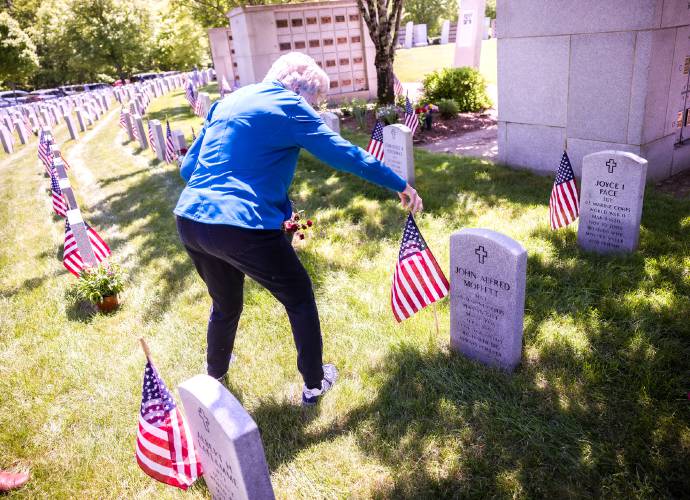 Marguerite Moffet adjusts the flag for the marker for her Marine veteran son, John, at the NH Veterans Cemetery in Boscawen on Tuesday, May 27, 2025.
