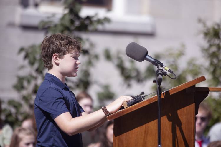 Nathan Dunlap, the essay competition winner for the Christa McAuliffe statue unveiling, reads his essay to the crowd at the State House on Monday.