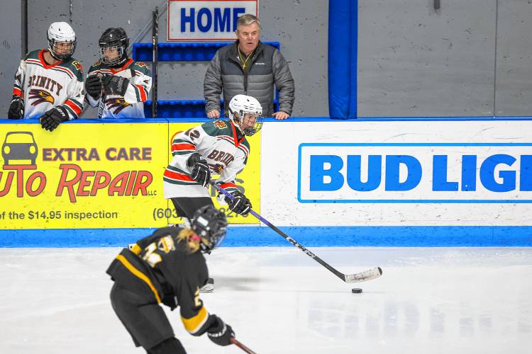 Bishop Brady-Trinity-Bow head coach, Dan Earley, now in his 14th season, instructs his team as senior captain Kylie Palmeter (12) carries the puck up the ice to start an attack.