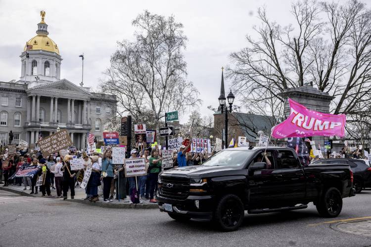 A Trump supporter drives past the crowd in front of the State House during the ‘Hands Off’ protest on Saturday, April 19, 2025.
