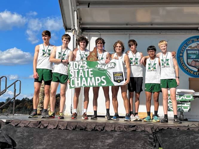 The Hopkinton boys’ cross country team poses with the championship plaque after winning the Division III title on Saturday at Manchester’s Derryfield Park.