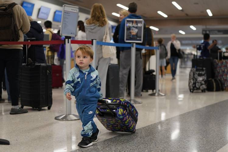 Cameron Suescun, 2, follows his mother through at the Nashville International Airport, Tuesday, Nov. 21, 2023, in Nashville, Tenn. Despite inflation and memories of past holiday travel meltdowns, millions of people are expected to hit airports and highways in record numbers over the Thanksgiving Day break. (AP Photo/George Walker IV)