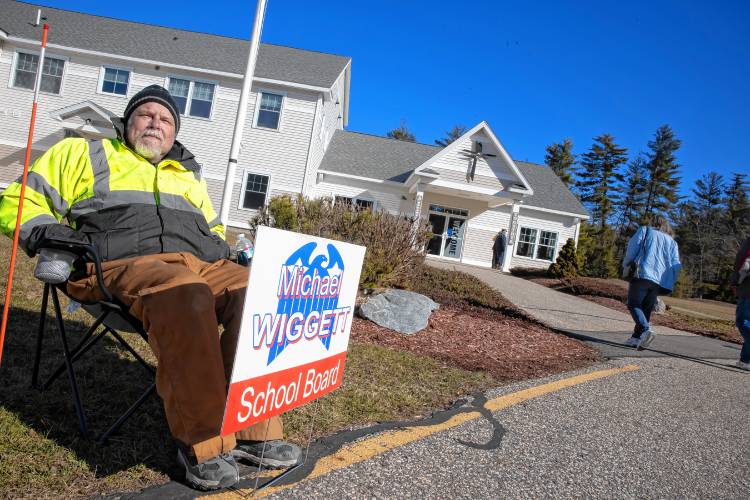 Epsom school board candidate Michael Wiggett sits out in the morning cold as voters walk into the Epsom Bible Church on Tuesday morning, March 12, 2024.
