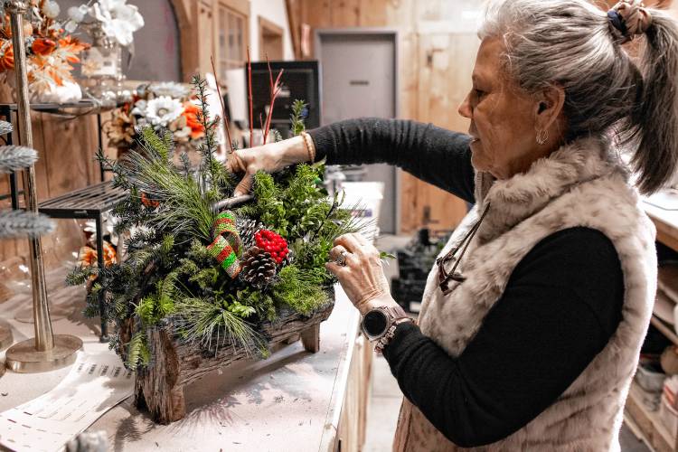 ABOVE: Jane Iarussi, vice president of Cole Gardens in Concord, puts the final touches on a custom made Christmas log basket she named the Pizzazz Christmas Basket on Tuesday. Iarussi says she’s grateful there is an extra week between Thanksgiving and Christmas this year.