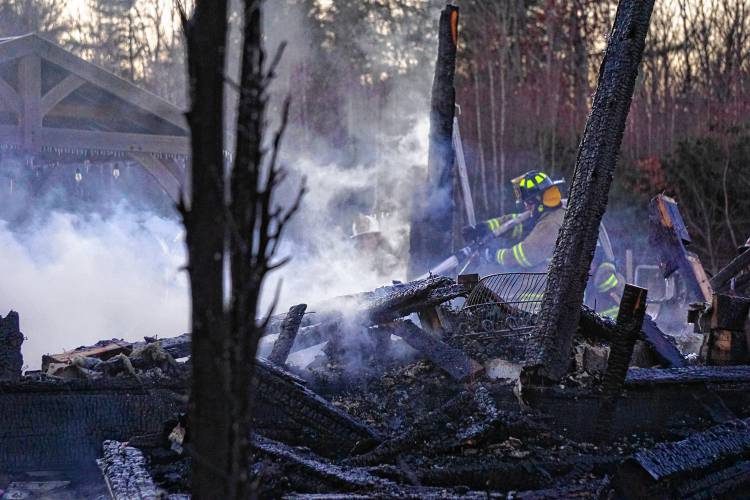 Firefighters try to extinguish hot spots after a fire ripped though a four-bedroom home on Barton Corner Road in Hopkinton on Wednesday afternoon. The structure was deemed a total loss. 