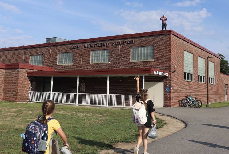 Bow Memorial School principal Adam Osburn stands on the roof to greet students arriving for the first day of school on Aug 29, 2022. Bow Memorial School principal Adam Osburn stands on the roof to greet students arriving for the first day of school on Aug 29, 2022.