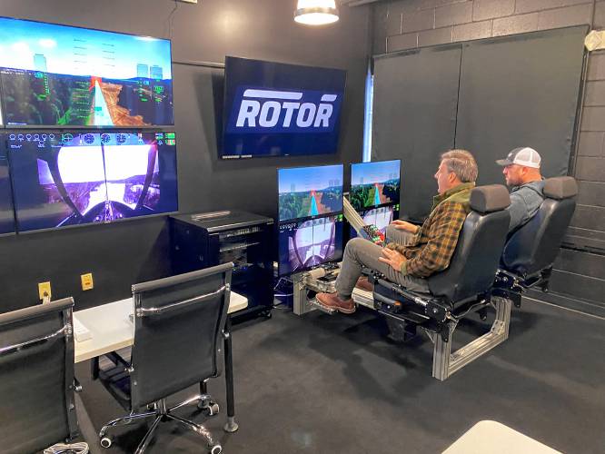 Gov. Sununu is shown video of a test flight in Henniker of the autonomous helicopter being built by Rotor, a startup based at Nashua Municipal Airport. Next to him is Ben Wood, test pilot for Rotor.