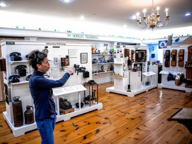Graham Gifford, director of programming at the New Hampshire Telephone Museum in Warner, points to a row of early phones at the museum on Friday, May 17, 2024.