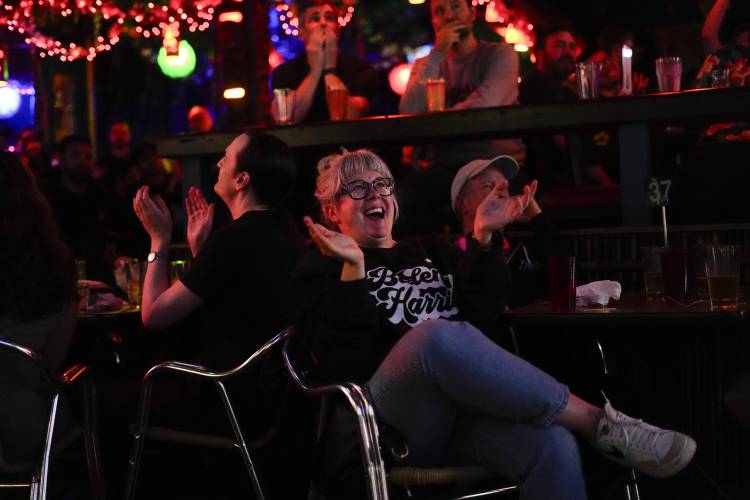 Amy Pottinger, wearing a Biden/Harris sweatshirt, claps as President Joe Biden comments on how Republican presidential candidate former President Donald Trump handled January 6th as people watch the presidential debate at Hula Hula, a tiki themed bar, Thursday, June 27, 2024, in Seattle. (AP Photo/Lindsey Wasson)