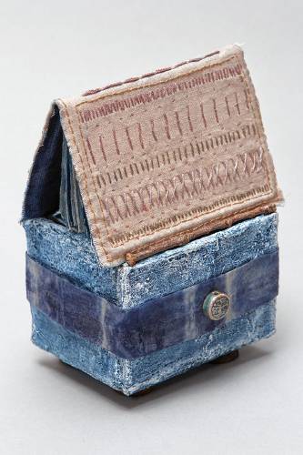 “Building A Home” by Susan Marsh is a tiny house of seven sketch books housed in an indigo dyed plaster box. 