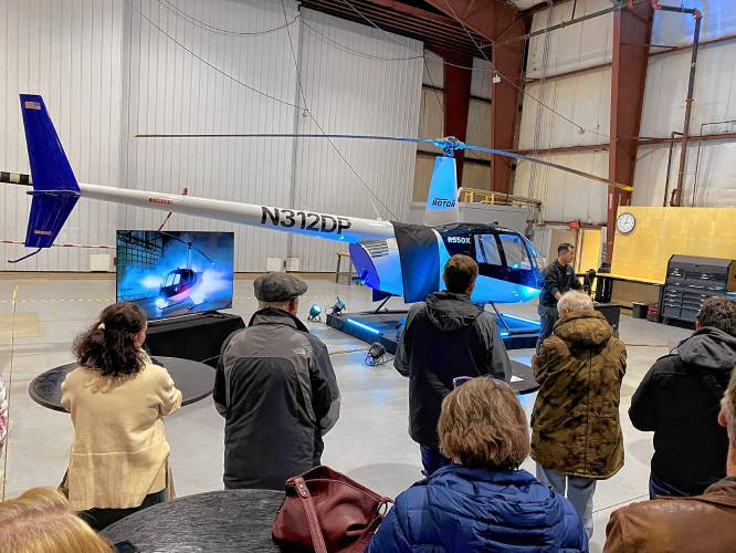 Rotor CEO Hector Xu talking at Tuesday’s company event inside Hangar 9 at Nashua Municipal Airport. Behind him is an example of a Robinson helicopter the company is altering to be autonomous.