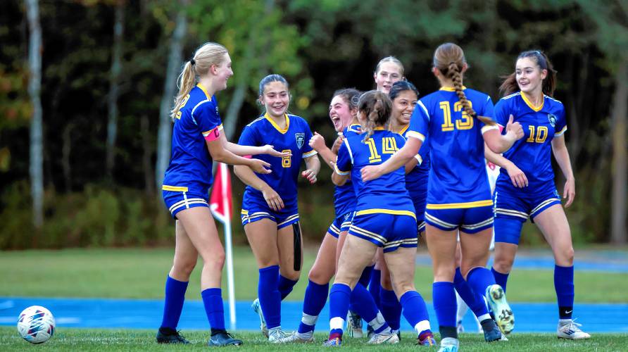 Teammates surround Bella Collins (center laughing) after she scored a goal against Hillsboro-Deering on Tuesday.