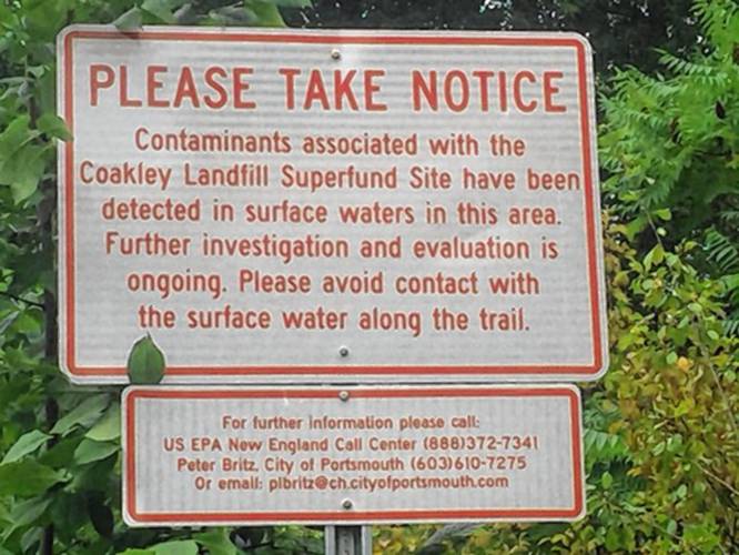 A sign warns the public about contaminants from the Coakley Landfill. A sign warns the public about contaminants from the Coakley Landfill.