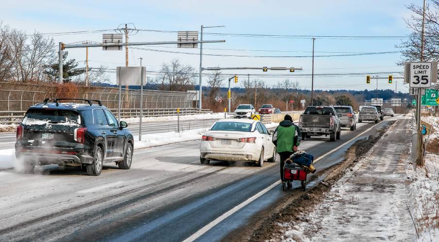 Raymond Blodgett walks with his belongings on I-393 eastbound in Concord on Tuesday, January 21, 2025. Blodgett was looking for his brother to help him replace a broken tire on his wagon.