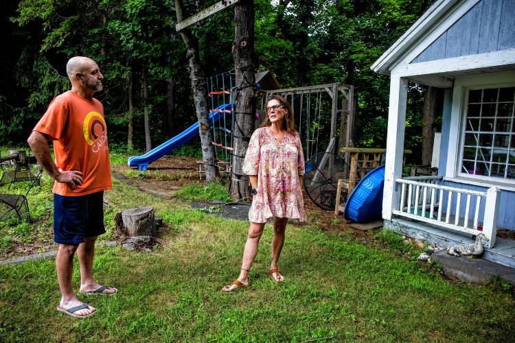 Robin Bach and her husband, Michael in the backyard play area that her children do not want to play in because of its proximity to the homeless encampment behind their home on North Main Street in Concord.
