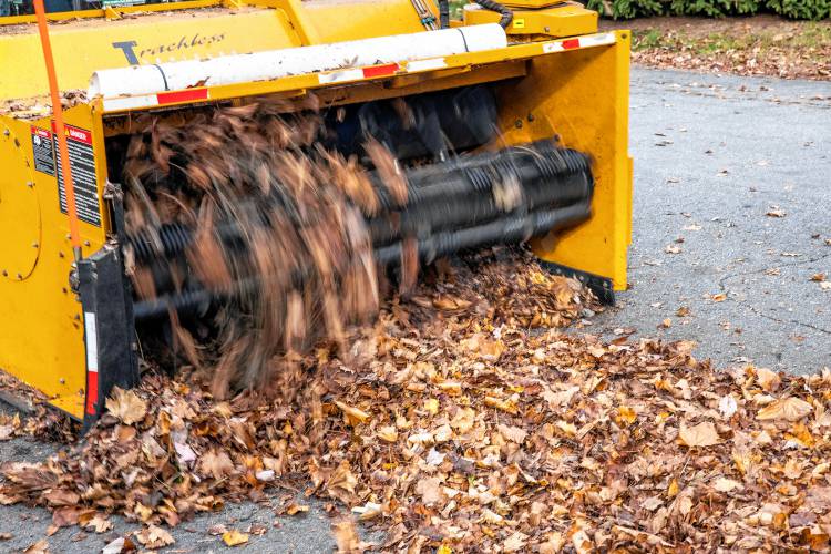 Leaves are swept up by the augur machine and blown into the backs of Concord dump trucks on Thursday, November 7, 2024.