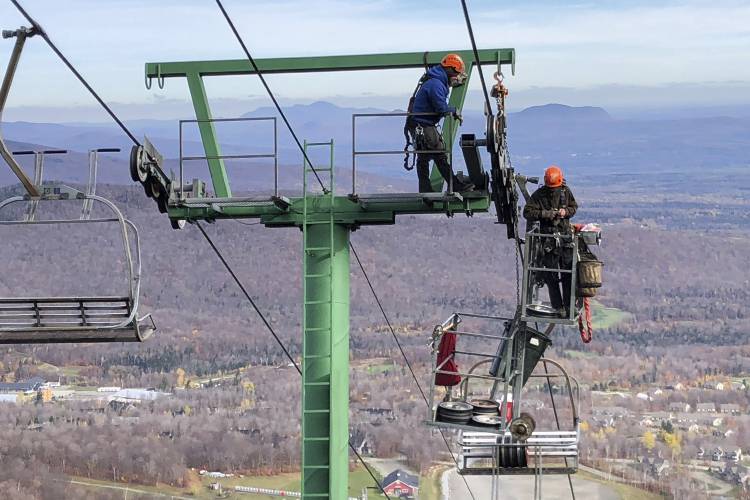 Workers do routine seasonal maintenance to a chairlift, Wednesday, Oct. 27, 2021, at Jay Peak Resort, in Jay, Vt., ahead of the upcoming season. After the previous season with mask mandates and other virus-related restrictions ski resorts are expecting a more normal season this winter. (AP Photo/Lisa Rathke) 