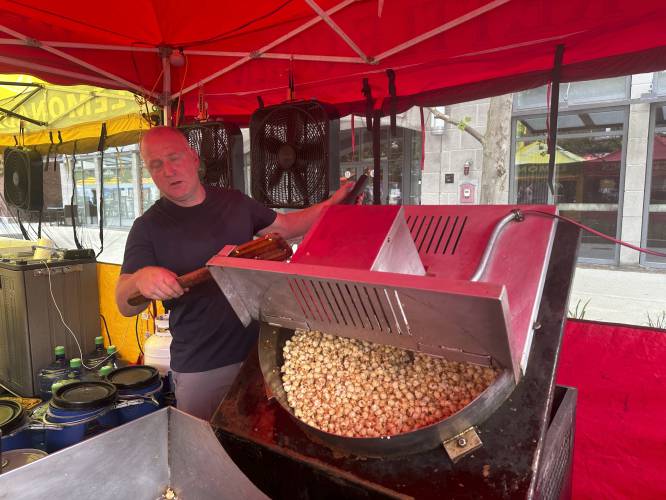 John DuPont prepares kettle corn at his booth at a Concord, N.H., street fair on Thursday morning, June 20, 2024, where the temperature was already near 90 degrees. (AP Photo/Kathy McCormack)