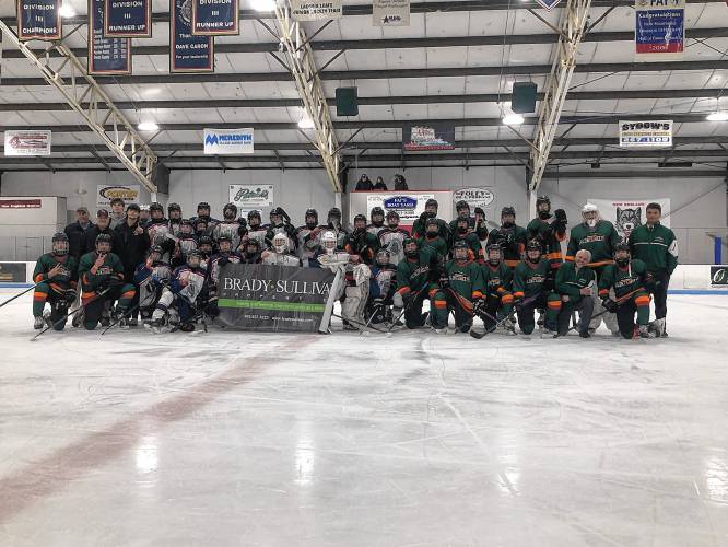 The Belmont-Gilford Bulldogs hockey team (white jerseys) and Monadnock-Fall Mountain (green jerseys) surround a banner after the Brady Sullivan Christmas Tournament final. The Bulldogs won the title with an 8-0 victory at Merrill Fay Arena in Laconia on Saturday.