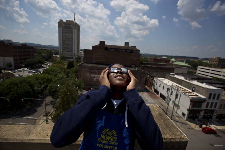 Justin Coleman, of Birmingham, Ala., holds his glasses up to his eyes as he watches the solar eclipse atop a parking structure on  Aug. 21, 2017, in Birmingham.