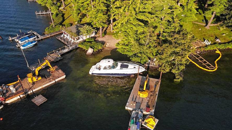 Drone photos taken last year show barges attempting to remove the 50-foot Sea Ray from its perch on the rocks near Keewaydin’s beach. 