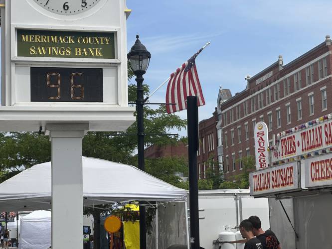 A bank clock overlooking the Market Days street fair in Concord, N.H., shows the temperature Thursday morning, June 20, 2024. A heat wave moved closer to a breaking point Thursday, with millions of people sweating it out for another day. (AP Photo/Kathy McCormack)