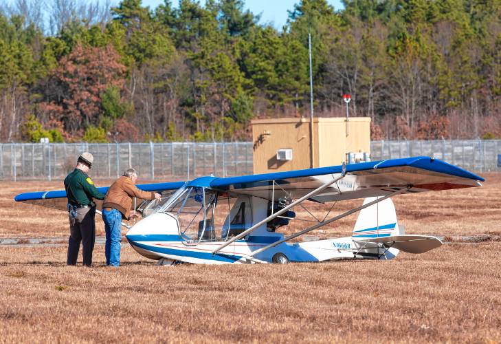 A New Hampshire State Police officer and a man inspect the plane that crash-landed Wednesday morning just north of the runway at the Concord Airport. No one was injured in the crash.