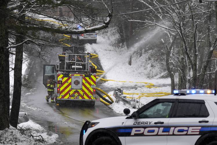 Police block a road as a firefighter works on a water line at a house fire, Thursday, April 4, 2024, in Derry, N.H. Derry Fire Chief Shawn Haggart said his department received reports of an explosion and responded to find a house fully engulfed in flames. (AP Photo/Charles Krupa)