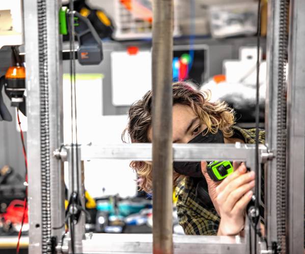 Tidal Force junior Veronica Galdieri looks over the new robot to re-check measurements from her CAD design as the team adapts the frame on Feb. 26.