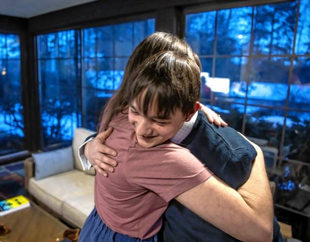Dawson Hayes gets a hug from his mom Carolyn Mallon in their Concord home. Dawson will again share his story with legislators on the House Child and Family Law Committee â how as a foster kid in New Hampshireâs state system, he lost $16,032 from Social Security benefits he would have been entitled to if he lived elsewhere. The state removed him from his biological parents care in 2021. Now he calls Carolyn Mallon and Simon Warwick mom and dad.