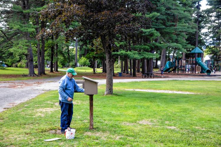 Ray Barrett puts the final touches on the Little Free Library at Rollins Park.