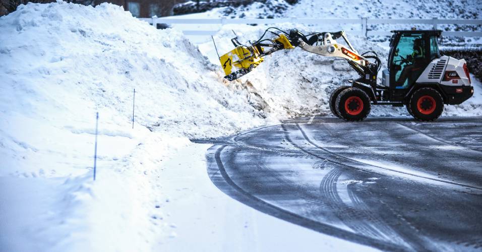 A front loader with a plow from Outdoor Pride pushes the snow from the latest snow storm into piles at the Dartmouth Health parking lot at sunrise on Thursday, February 13, 2025. Another storm is due this weekend.