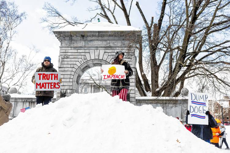 Harry Seidel (left), from Warner and Lauren Winterholer of Rollinsford joined the hundreds of people by climbing up a snow mound at City Plaza in front of the State House on Monday.