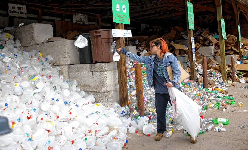 Sarah Kelley of Hopkinton throws a plastic jug into the recycling pile at the Hopkinton Webster Transfer Station on Wednesday.