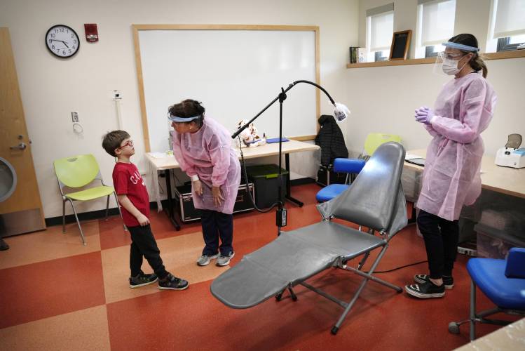 Clayton Warner is greeted by dental hygienist Mary Davis before a dental exam at the Christa McAuliffe School in Concord, N.H., Wednesday, Feb. 21, 2024. Dental assistant Crystal Muzzo stands at right. There is a push to revive and expand school-based programs that often serve as a child's first dental visit and offer critical preventive care. (AP Photo/Robert F. Bukaty) 