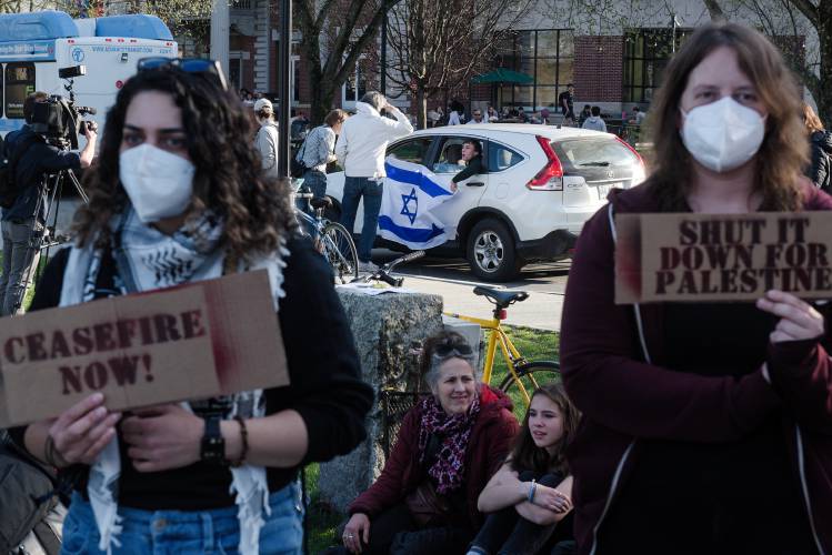 Ahlam Abuawad, left, and Emily Simpson, both members of Upper Valley for Palestine, listen to a speaker during a protest of the Israel-Hamas War on the Dartmouth College Green in Hanover, N.H., as men in a passing car unfurl an Israeli Flag on Wednesday, May 1, 2024. (Valley News - James M. Patterson) Copyright Valley News. May not be reprinted or used online without permission. Send requests to permission@vnews.com.