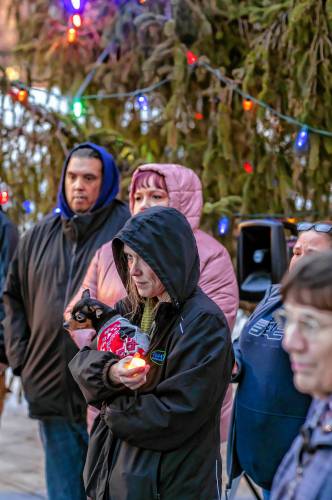 Nicole Corbett holds her friend’s dog, Cali, as she listens to the speakers at the vigil at City Plaza to honor the 54 homeless people who died in 2024.