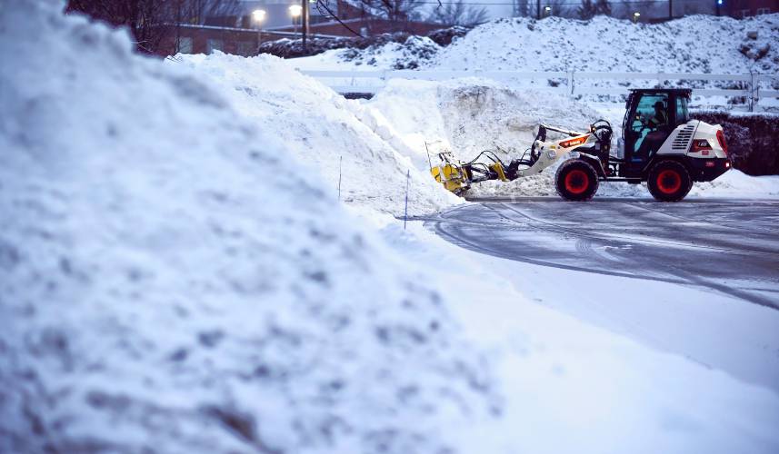 A front loader with a plow from Outdoor Pride pushes the snow from the latest snow storm into piles at the Dartmouth Health parking lot at sunrise on Thursday, February 13, 2025. Another storm is due this weekend.